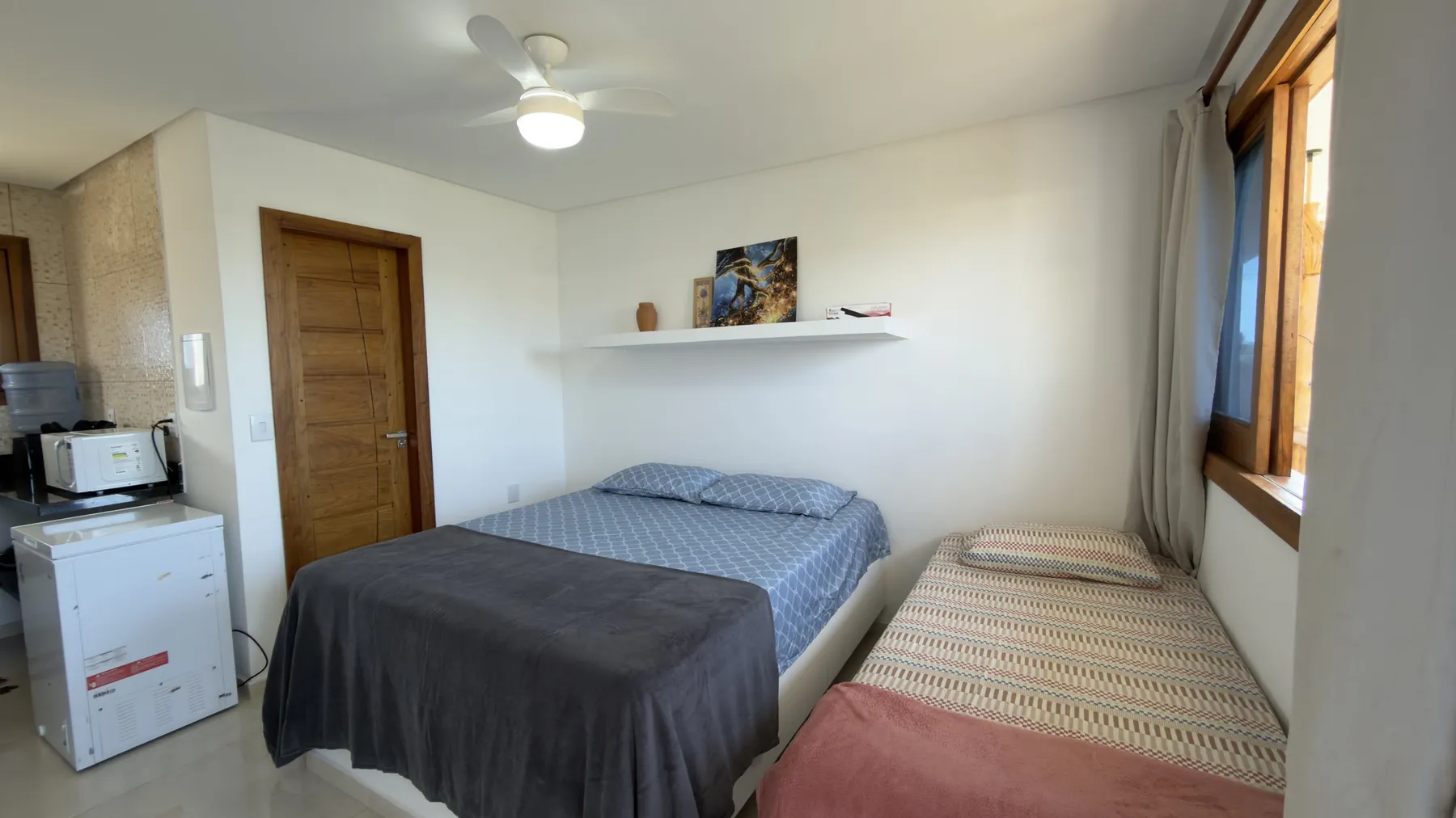 Flat com cama de casal, cama de solteiro e cozinha compacta ao fundo