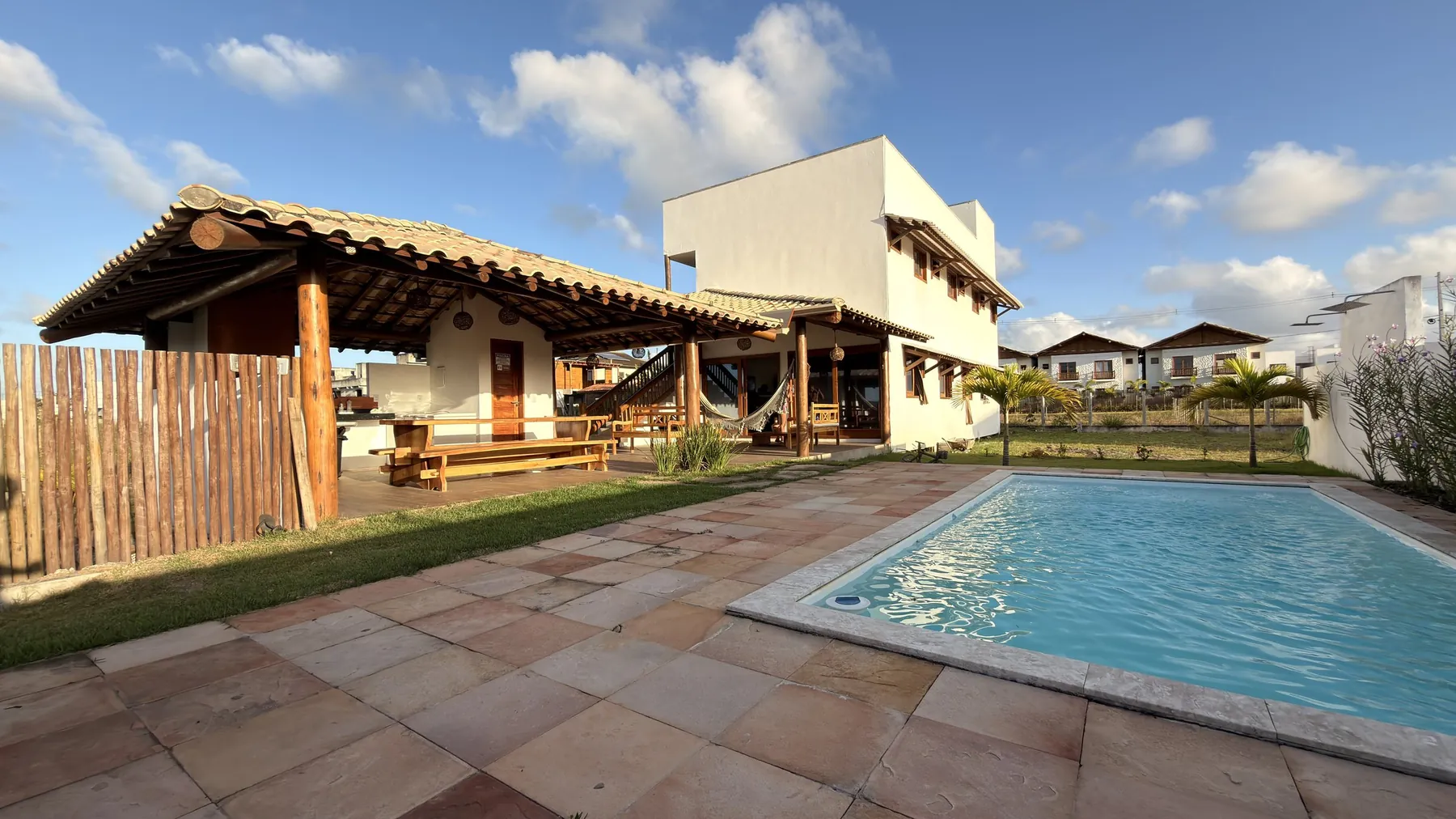 Piscina com a casa e a área coberta ao fundo